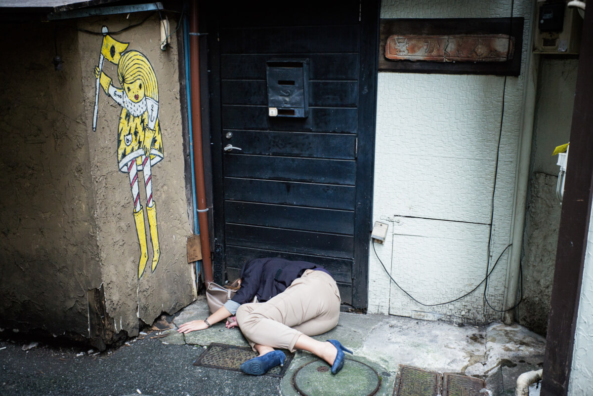 Japanese woman passed out drunk in a dirty Tokyo alleyway.