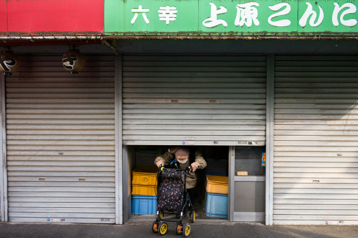 old lady in old Tokyo exiting her old shuttered shop